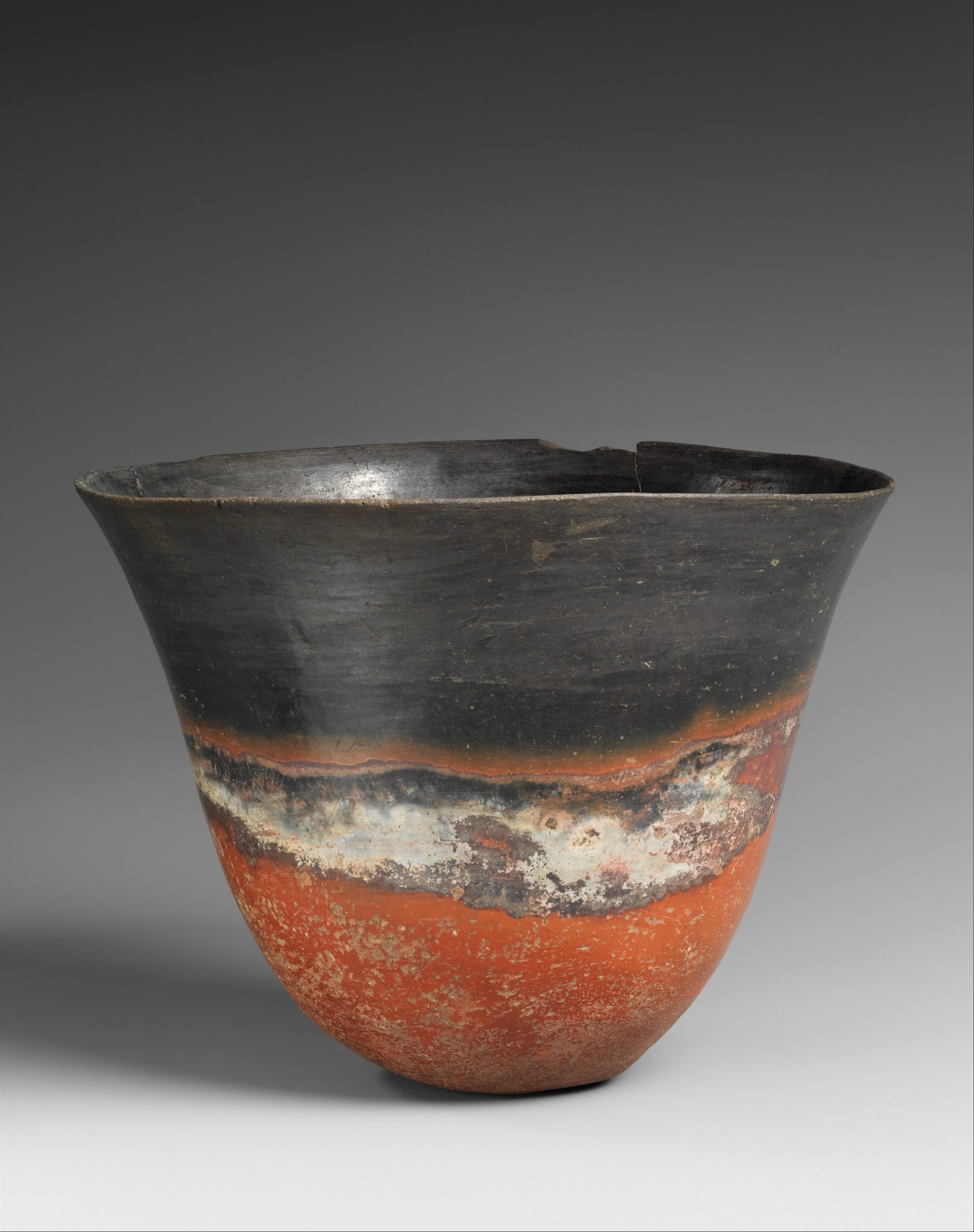 A hand-formed Kerma pottery beaker with a polished black upper surface and red lower body