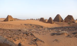 Royal pyramids at Meroe in Sudan, with steep stone sides rising from a sandy landscape in evening light.