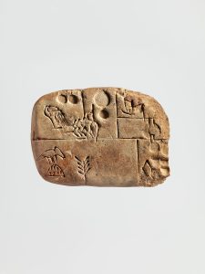 Small tan Mesopotamian clay tablet divided into sections containing circular impressions and incised signs.